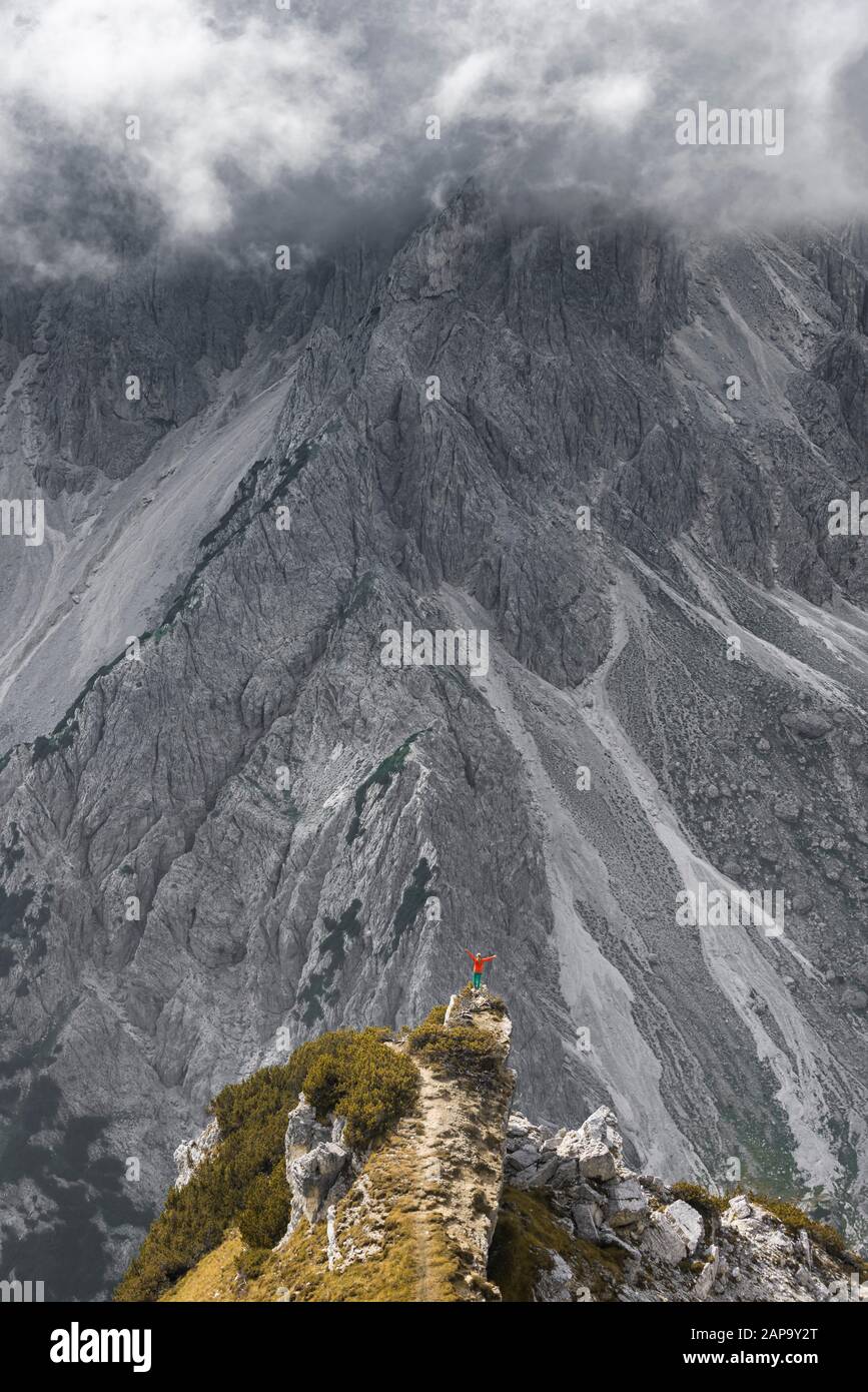 Femme debout à un degré, derrière les rochers, humeur dramatique, derrière le pied de montagne de Cimon di Croda Liscia, Auronzo di Cadore, Belluno, Italie Banque D'Images