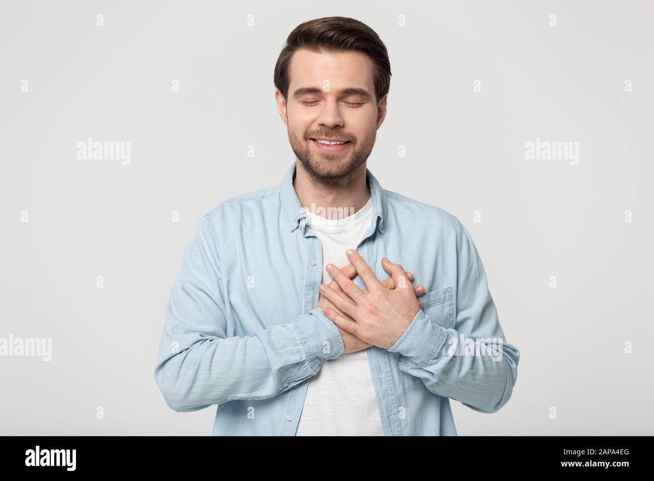 Portrait de la tête jeune homme repliant les mains croisées sur la poitrine. Banque D'Images