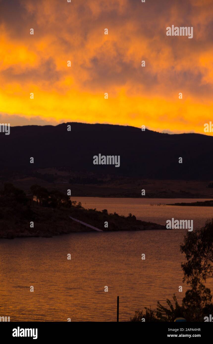 Des oranges lumineuses coucher de soleil au bord du lac Jindabyne dans les montagnes enneigées australie Banque D'Images