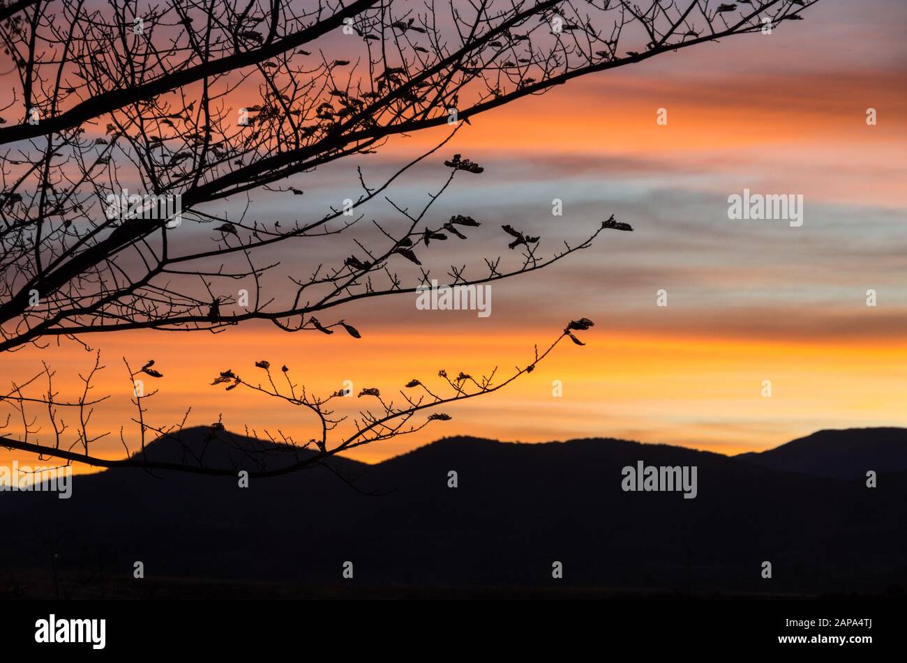 Des oranges lumineuses coucher de soleil au bord du lac Jindabyne dans les montagnes enneigées australie Banque D'Images