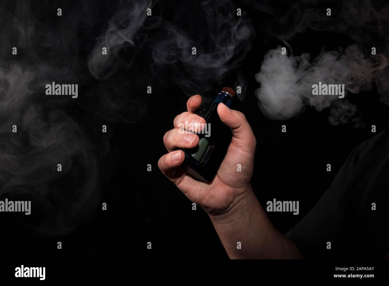 Le raisin électronique entre les mains d'un homme qui fume et libère des bouffées de fumée. Dangereux pour la dépendance à la santé. Appareil fumeur à la mode. Un problème de santé Banque D'Images