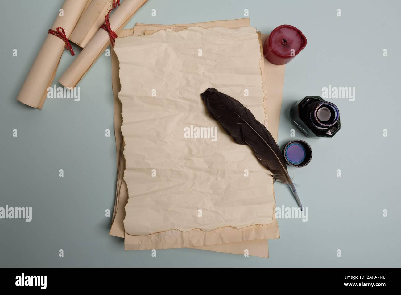 Plume de corbeau, inkwell et vieux papier jauni sur fond rouge. Copier l'espace. Vieille lettre. Banque D'Images