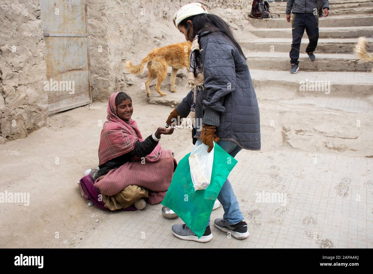 Jammu CACHEMIRE, INDE - 19 MARS : Les Voyageurs thaïlandais donnent de l'argent à la vieille femme indienne beggar ou intouchables caste assis et mendier sur le marché au le Banque D'Images