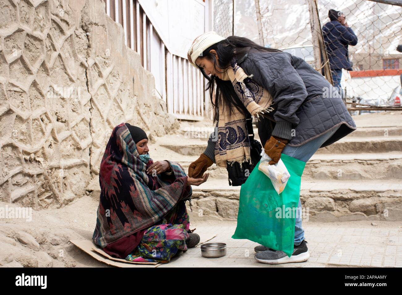 Jammu CACHEMIRE, INDE - 19 MARS : Les Voyageurs thaïlandais donnent de l'argent à la vieille femme indienne beggar ou intouchables caste assis et mendier sur le marché au le Banque D'Images