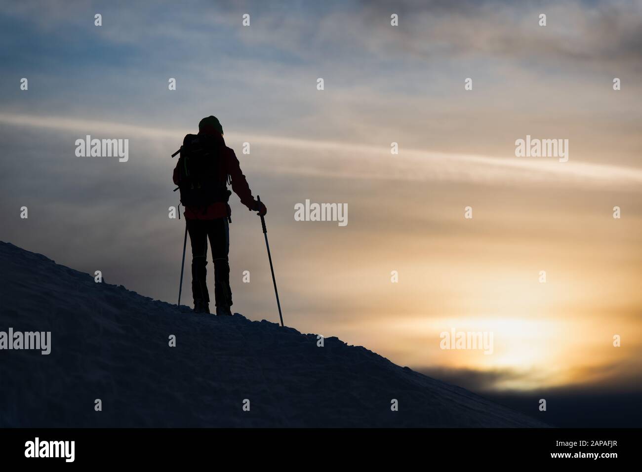 Un skieur alpiniste regarde le soleil descendre Banque D'Images