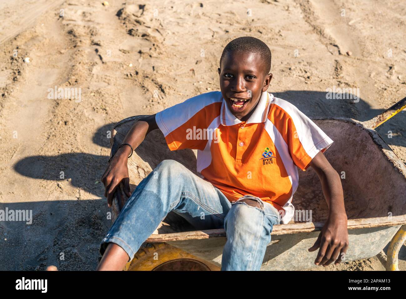 Lachender Junge sitzt dans einer Schubkarre, Tanji, Gambie, Westafrika | rire garçon assis dans une brouette, Tanji, Gambie, Afrique de l'Ouest, Banque D'Images