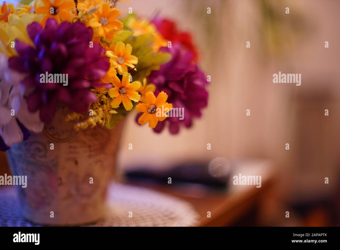 Un bouquet luxuriant de fleurs artificielles dans un pot de fleurs se dresse sur une table dans le salon. Banque D'Images