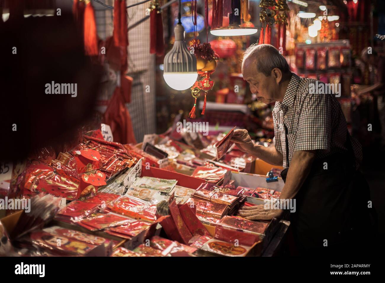 Un vieil homme regarde une collection d'enveloppes rouges avec différents dessins pendant la célébration dans Chinatown.des articles tels que des mots et des expressions favorables sont généralement achetés et affichés par les Chinois pour annoncer dans le nouvel an chinois. Banque D'Images