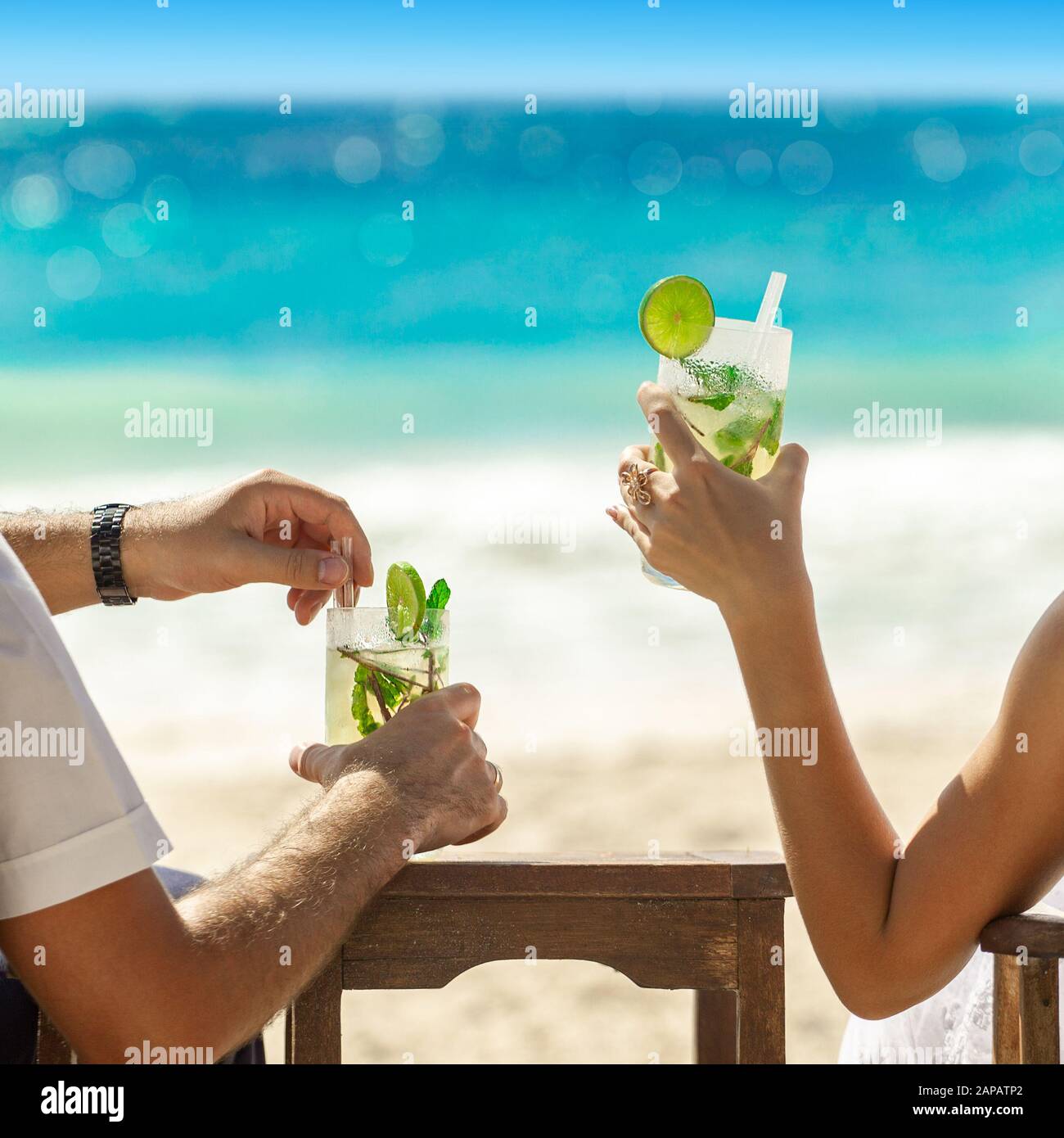 Deux verres à cocktail dans les mains sur fond marin. Concept de vacances d'été. Super mojito sur la plage. Reposez-vous sur les vacances à la ceinture. Carré Instagram Banque D'Images