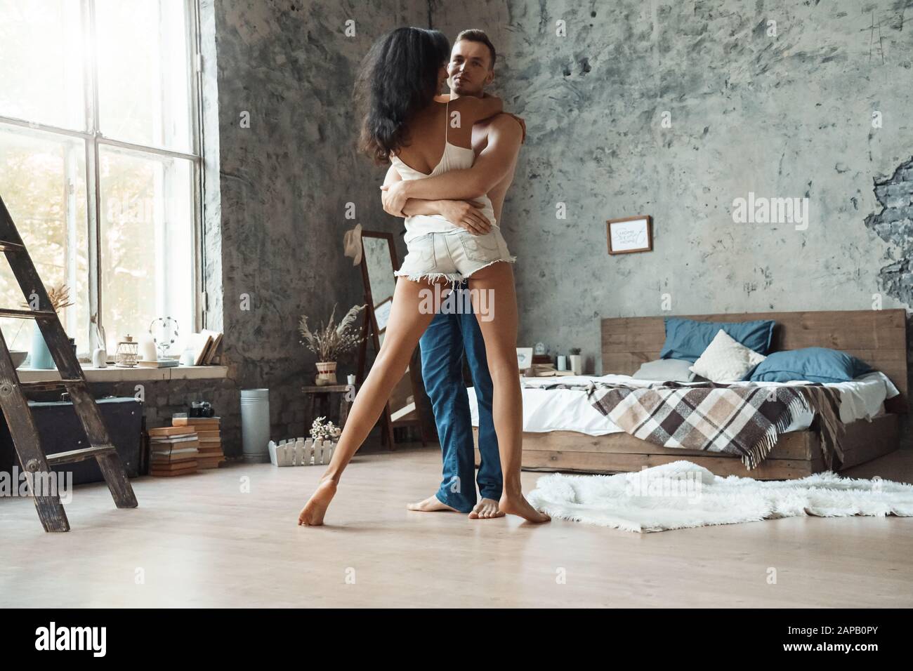 Couple De Course Mixte. Jeune homme et femme dans la chambre embrassant la danse joyeuse Banque D'Images