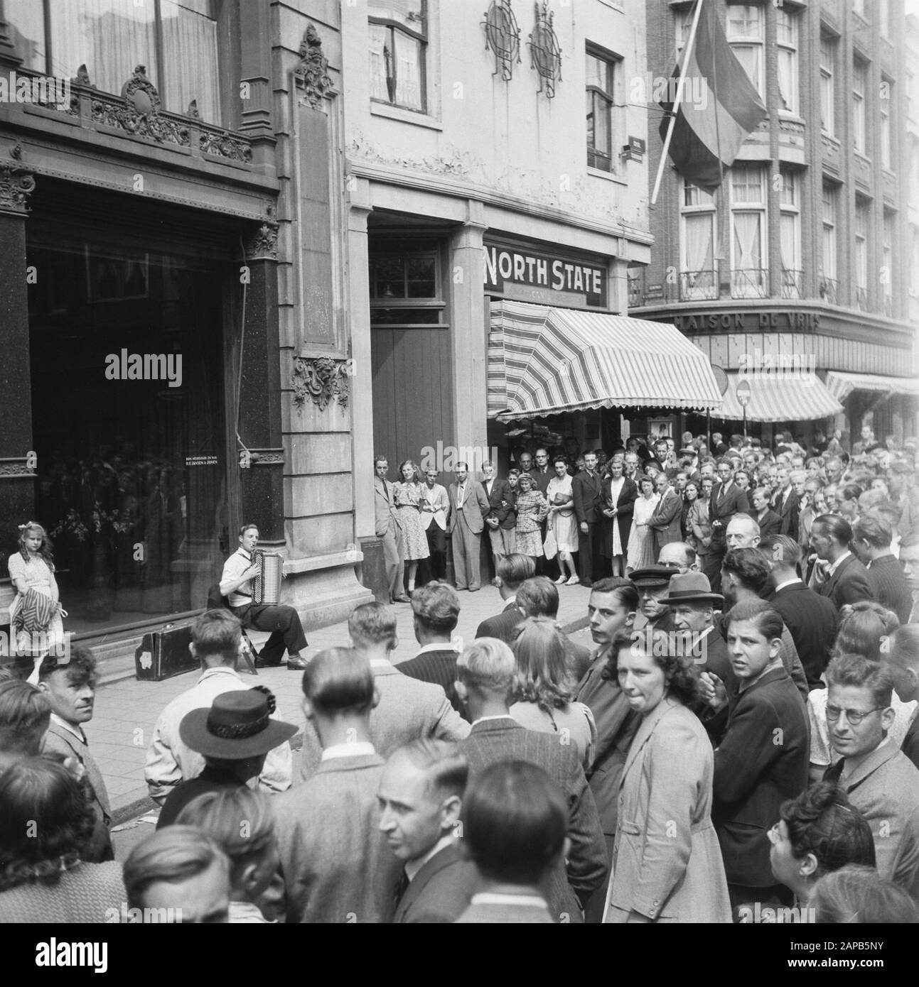 Les divertissements populaires à Amsterdam. Rép. Des diverses festivités liées à la libération dans la capitale Description: [Accordéoniste pour la grande fenêtre de la Royal Furniture Factory et Magaijn H.F. Jansen en Zoon aan de Spui. Une fille est prêtée à côté de lui contre un pilier Date: 28 juin 1945 lieu: Amsterdam, Noord-Holland mots clés: Festivals de libération, seconde Guerre mondiale Banque D'Images