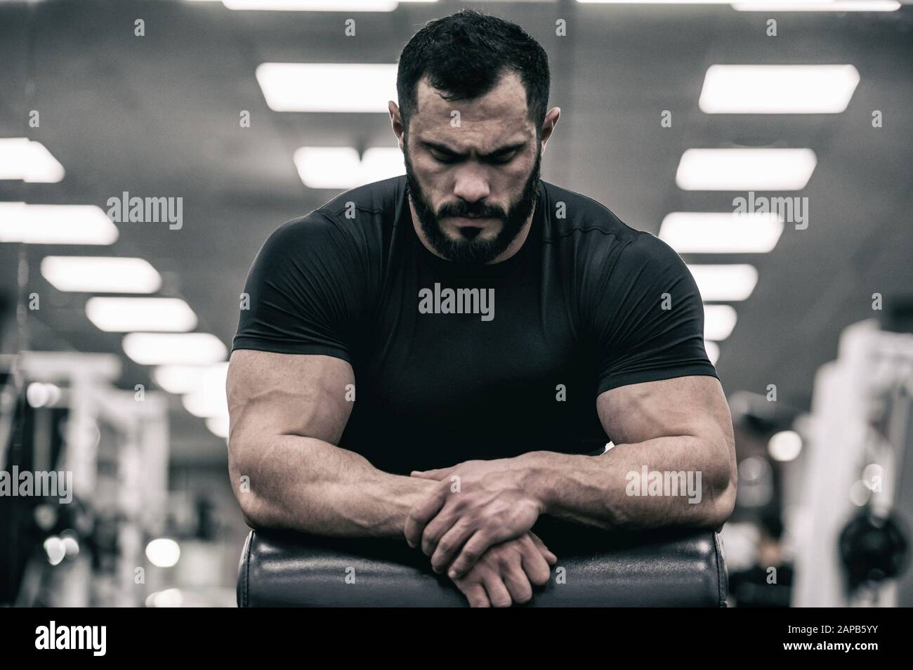 esprit mental sport motivation concept de jeune homme fort avec barbe portant maillot noir concentration détente dans la salle de sport Banque D'Images