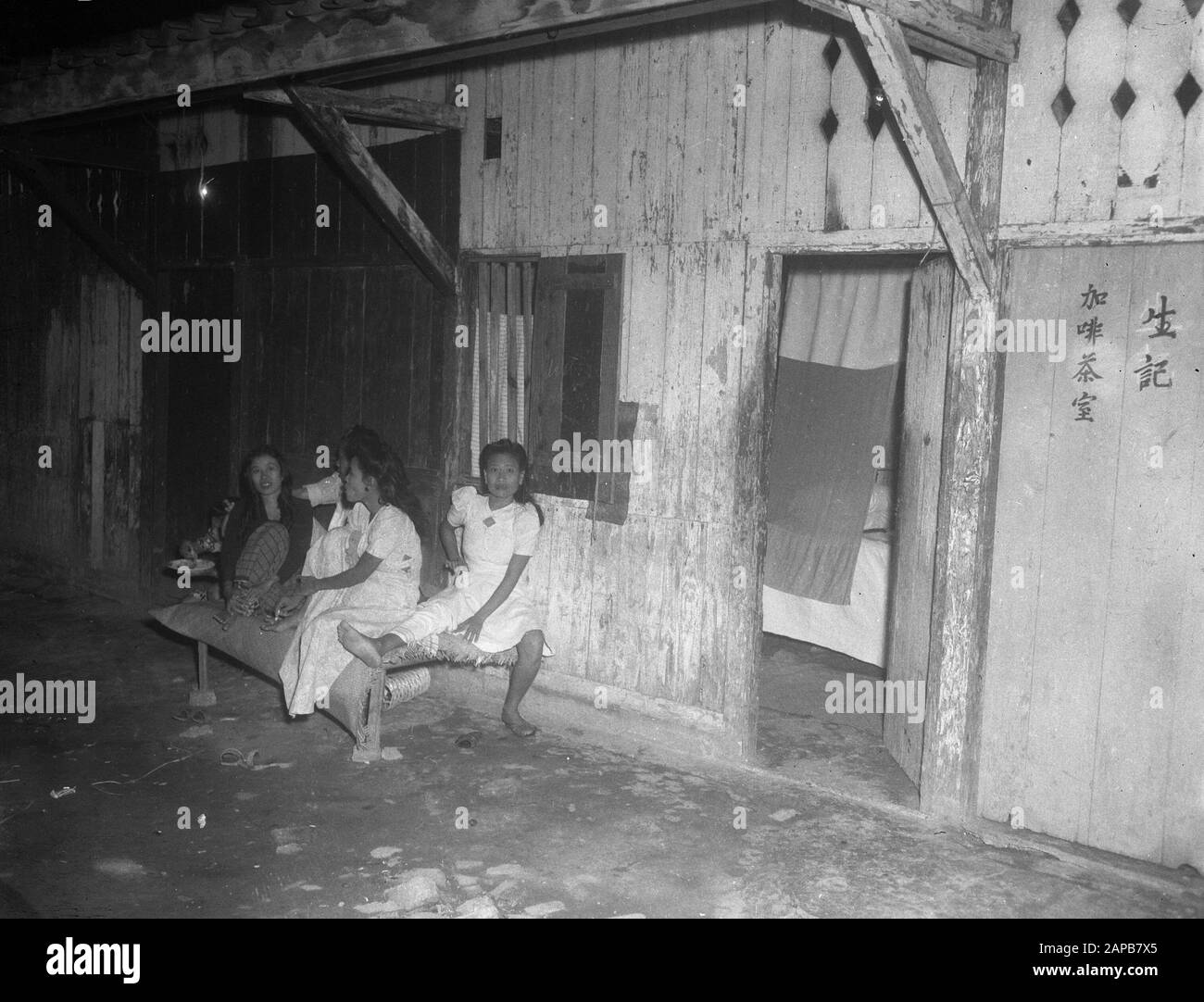 [Femmes (prositiuées?) , asseyez-vous sur un banc devant un barrack en bois. Batavia (Jakarta), Indonésie. Personnages chinois droits sur les étagères] Service de collecte de photos pour l'armée Contacts Indonésie Rapport médical le docteur Nanning [prostitution?] Date 22 juin 1948; Banque D'Images