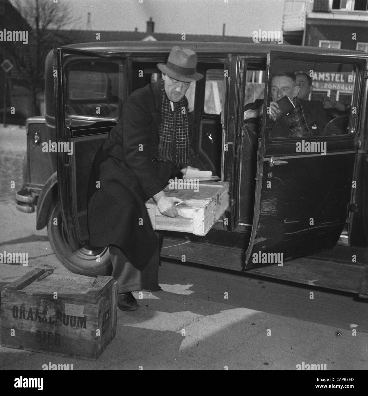 Répétition générale du jeu de libération, qui se déroulera les 4 et 6 mai 1946 dans le stade olympique Description: Le CCD [Service de contrôle central]. Ce responsable du CCD découvre 300 œufs. Les œufs sont chargés hors de la voiture. Le transporteur reçoit un billet Annotation: Le Service central de contrôle était une continuation du Service central de contrôle De Crise, qui était principalement destiné à lutter contre le commerce noir. Le CCD a été transformé en 1954 en Service général d'inspection du Ministère de l'Agriculture Date : 3 mai 1946 mots clés : économie, Œufs, services de détection Banque D'Images