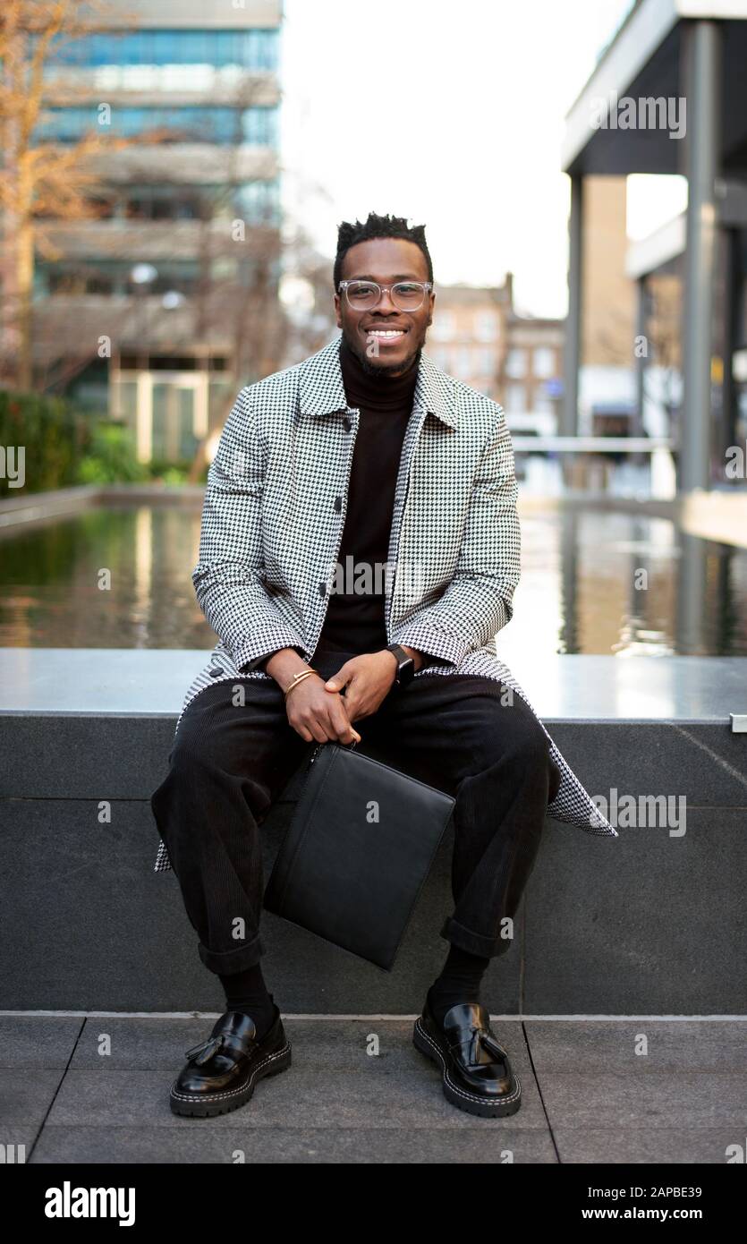 Portrait extérieur de souriant homme noir dans un environnement de bureau moderne, portant un vêtement habillé / professionnel décontracté. Mode Blogger avec modèle de libération Banque D'Images