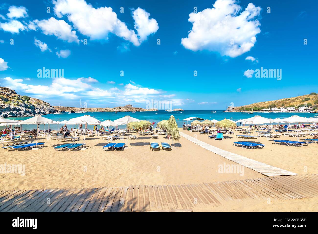 Vue sur la plage de sable et les personnes en mer dans la baie de Lindos, nuages sur le ciel bleu (Rhodes, Grèce) Banque D'Images