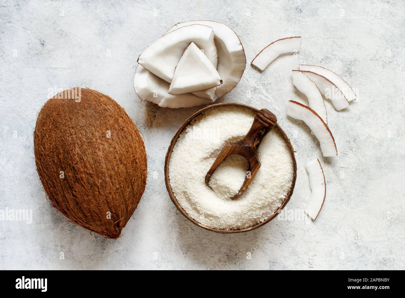 Farine de noix de coco dans un bol en bois avec morceaux de noix de coco sur une table blanche vue dessus Banque D'Images