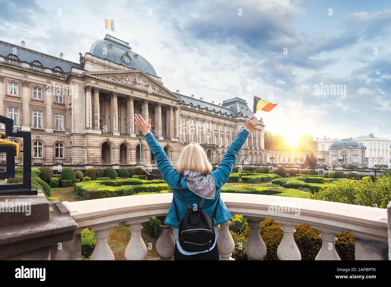 Femme touriste dans des vêtements décontractés se tient avec son dos à la caméra et agitant le drapeau de la Belgique contre le fond du Palais Royal à Bruxelles Banque D'Images