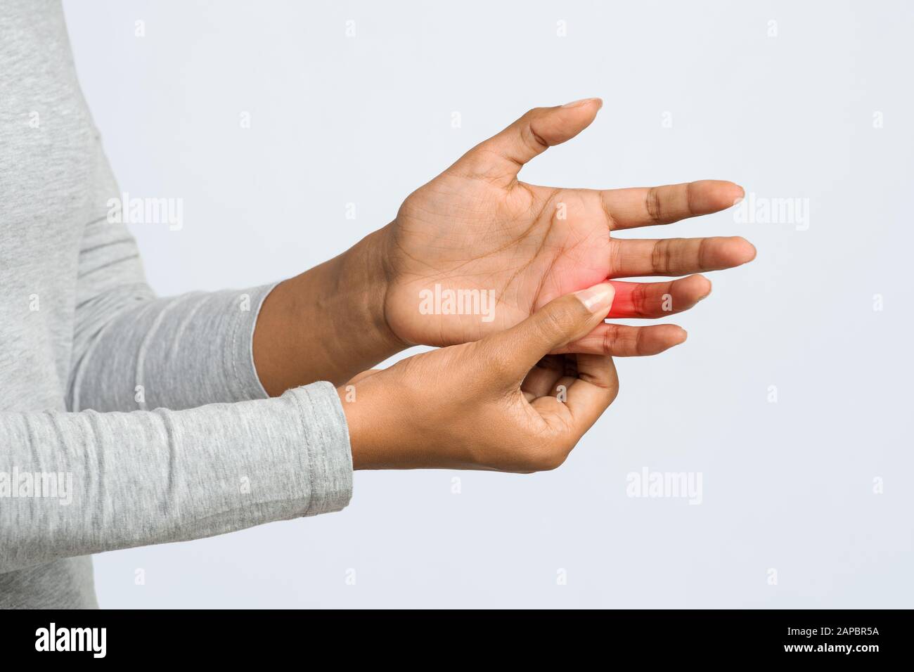 Jeune femme massant son doigt douloureux, court Banque D'Images