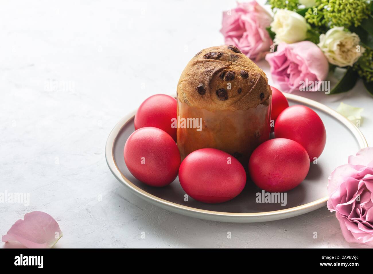 Gâteau de Pâques, œufs de Pâques rouges et fleurs au teint naturel sur table festive de vacances Banque D'Images