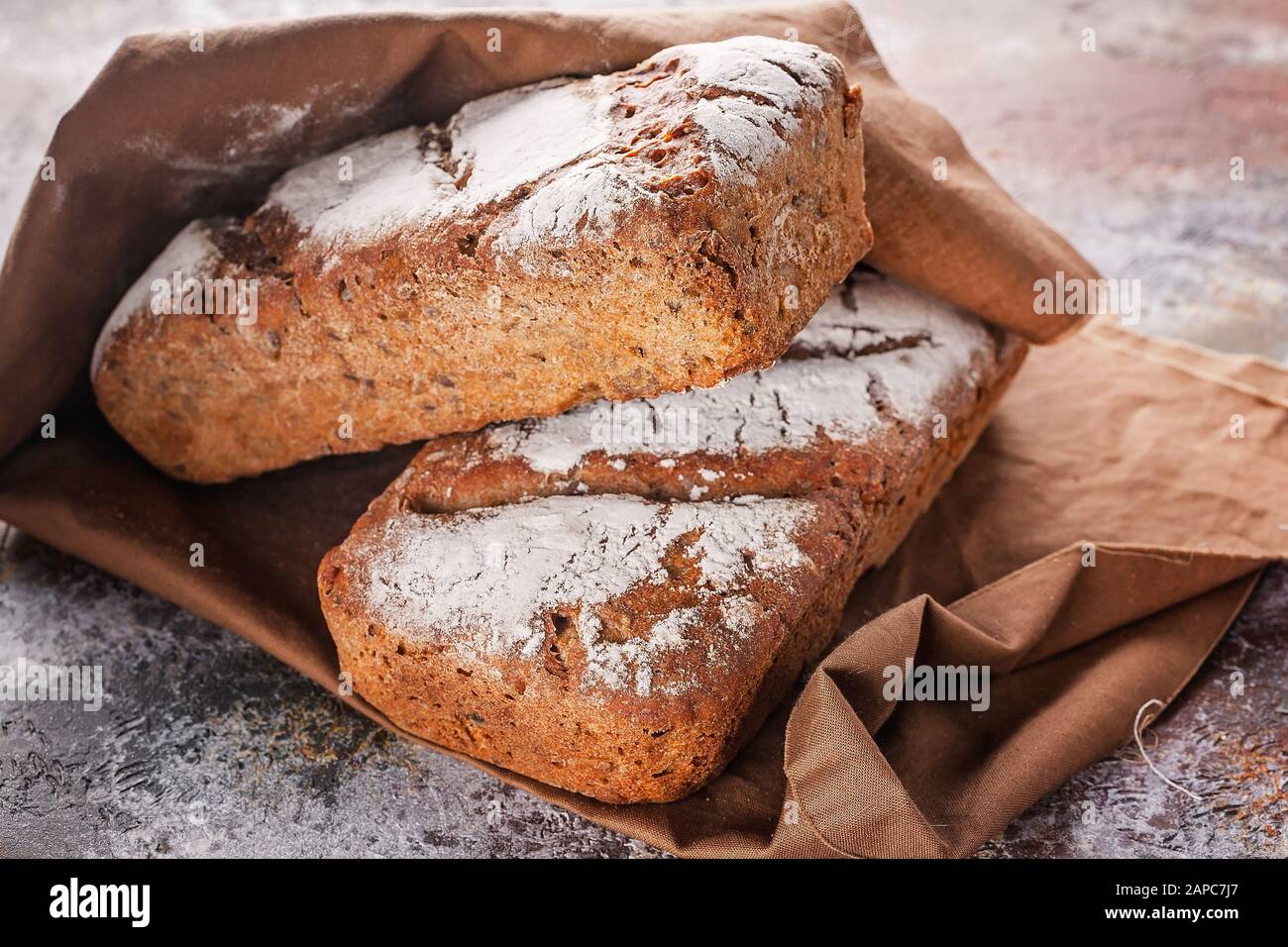Gros pain frais au levain avec graines de tournesol et de citrouille sur une serviette brune. Banque D'Images