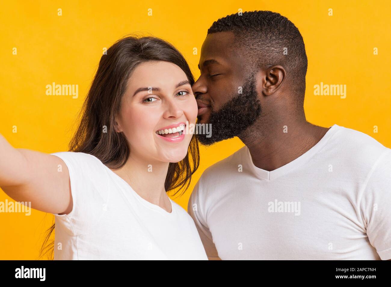 Couple multiracial romantique prenant selfie, affectueux gars noir embrassant sa petite amie Banque D'Images