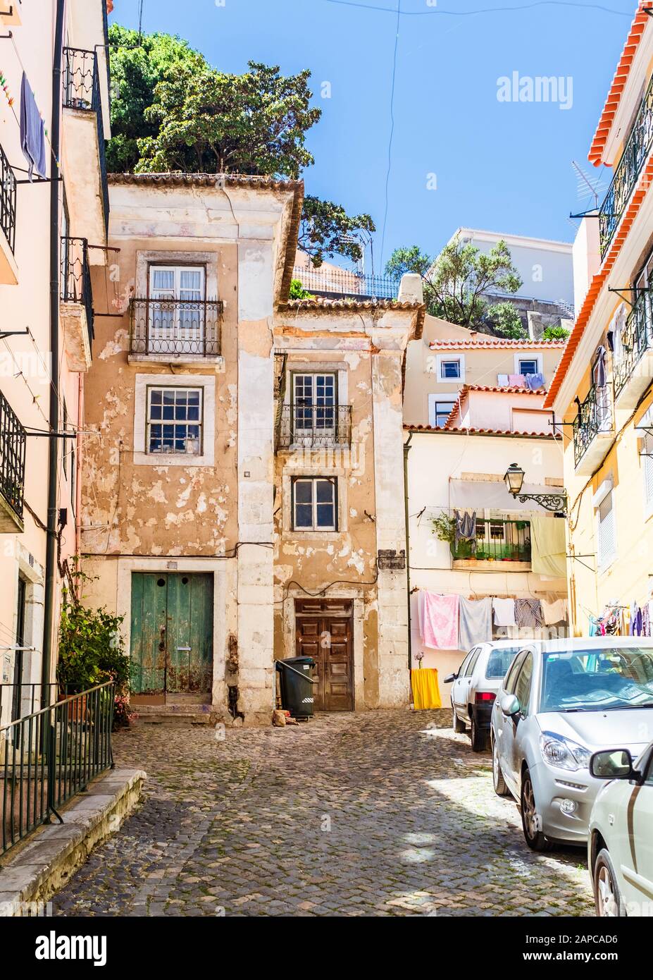 Vue sur la rue du quartier d'Alfama à Lisbonne avec des voitures stationnées près de bâtiments historiques. Banque D'Images