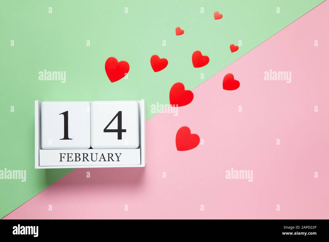 Calendrier perpétuel à la date du 14 février, coeurs confettis de différentes tailles rouges sur fond rose et vert bicolore. Pose plate. Vue de dessus. Saint-Valen Banque D'Images