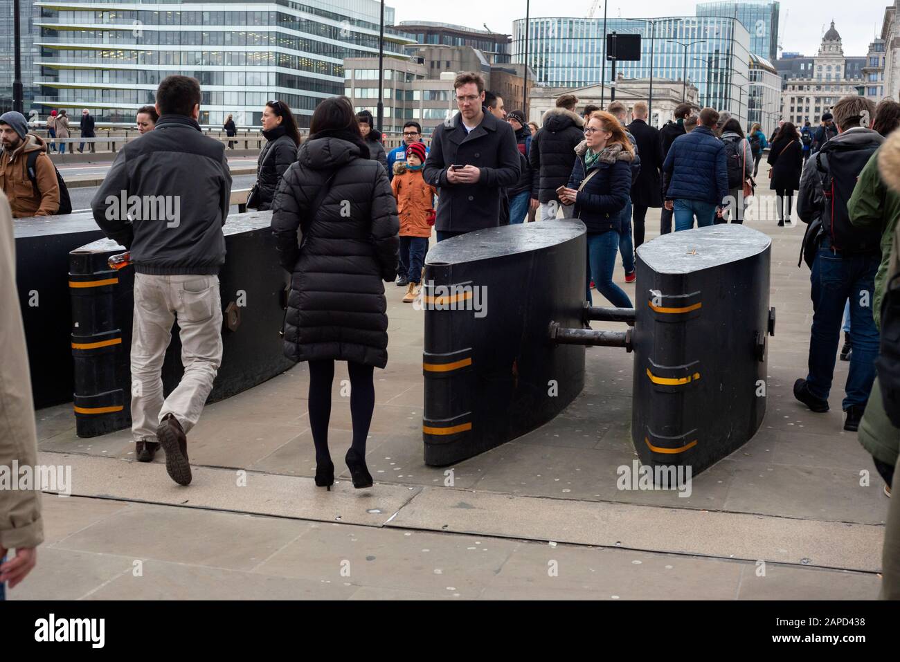Piétons personnes London Bridge navetteurs passant devant les bornes de sécurité anti-terrorisme et les barrières à London Bridge, Londres Royaume-Uni à partir de 2020 Banque D'Images