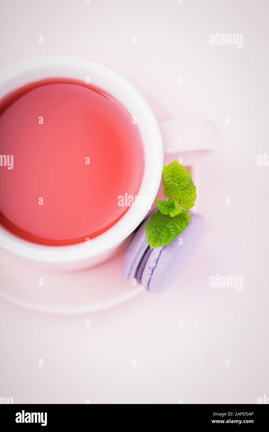 Thé aux fruits, macaron blackberry ou macaron avec feuille de menthe sur fond rose pâle, espace de copie Banque D'Images