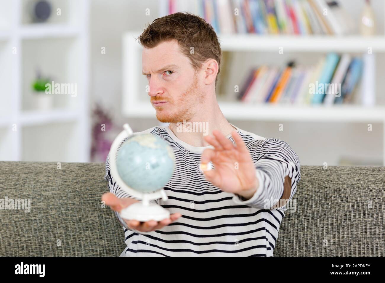 jeune homme tenant globe et carte sim à la maison Banque D'Images