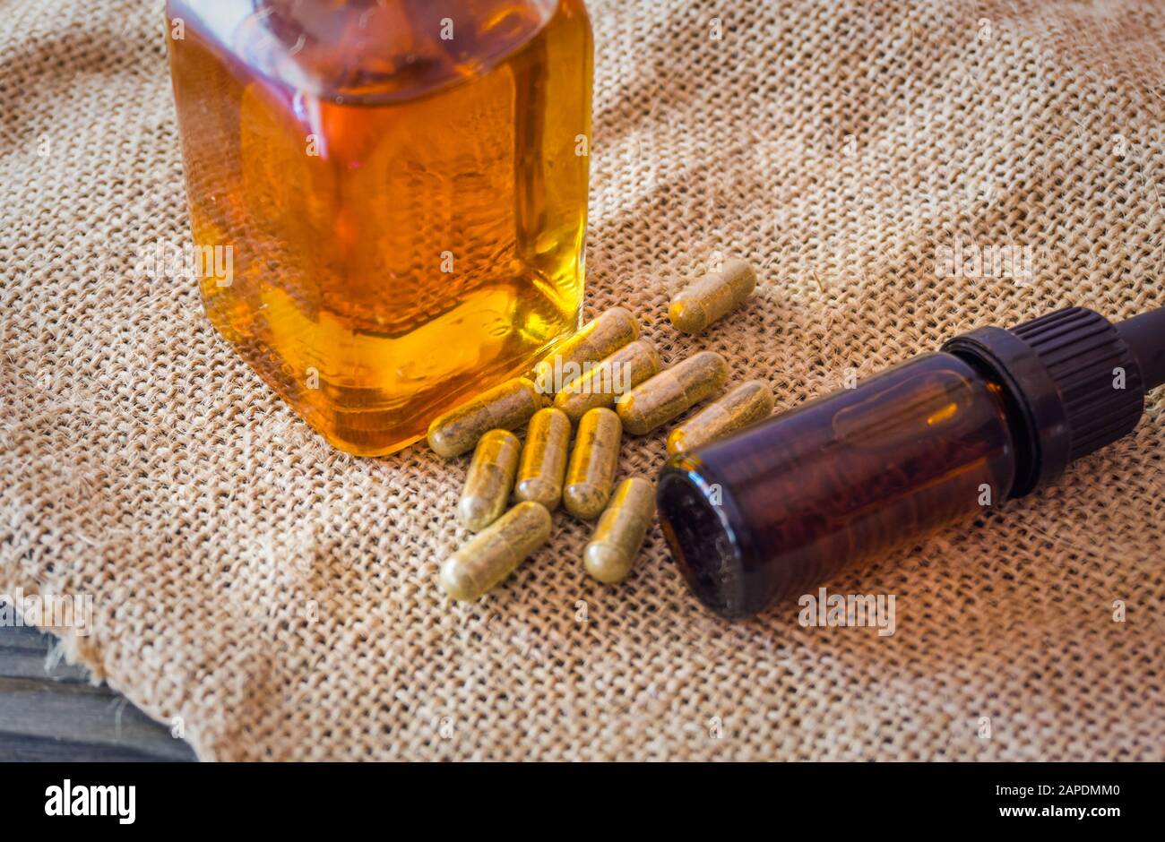 Bouteille de verre avec des huiles de cannabis CBD THC et des pilules de CBD sur tissu de chanvre, concept médical de marijuana Banque D'Images