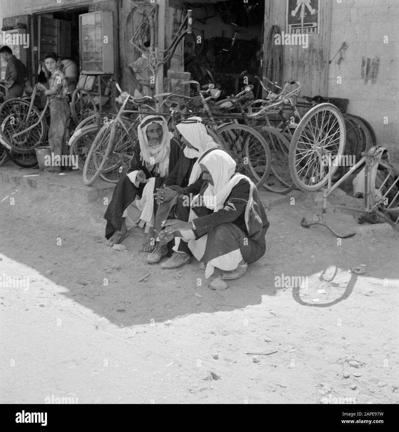 Israël 1960-1965: Bedouins in Beersewa (Beer Sheva) Description: Bedouins, assis au bord de la rue par un vélo Date: 1 janvier 1960 lieu: Beersewa, Israël mots clés: Bedouins, Bicyclemakers, peignoirs, hommes, images de rue Banque D'Images