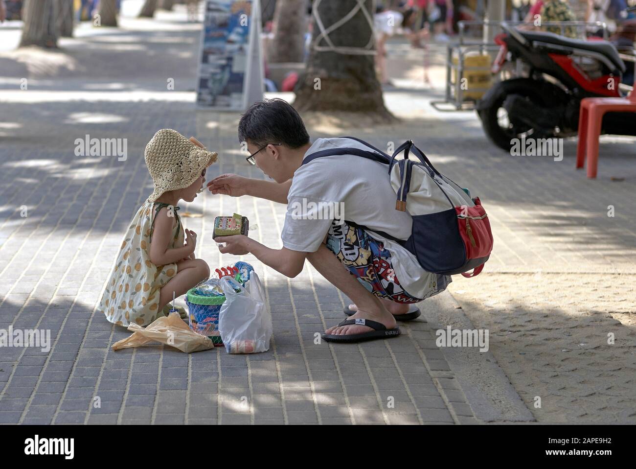 L'homme nourrit l'enfant; le jeune père nourrit sa jeune fille dans la rue; Thaïlande Asie du Sud-est Banque D'Images