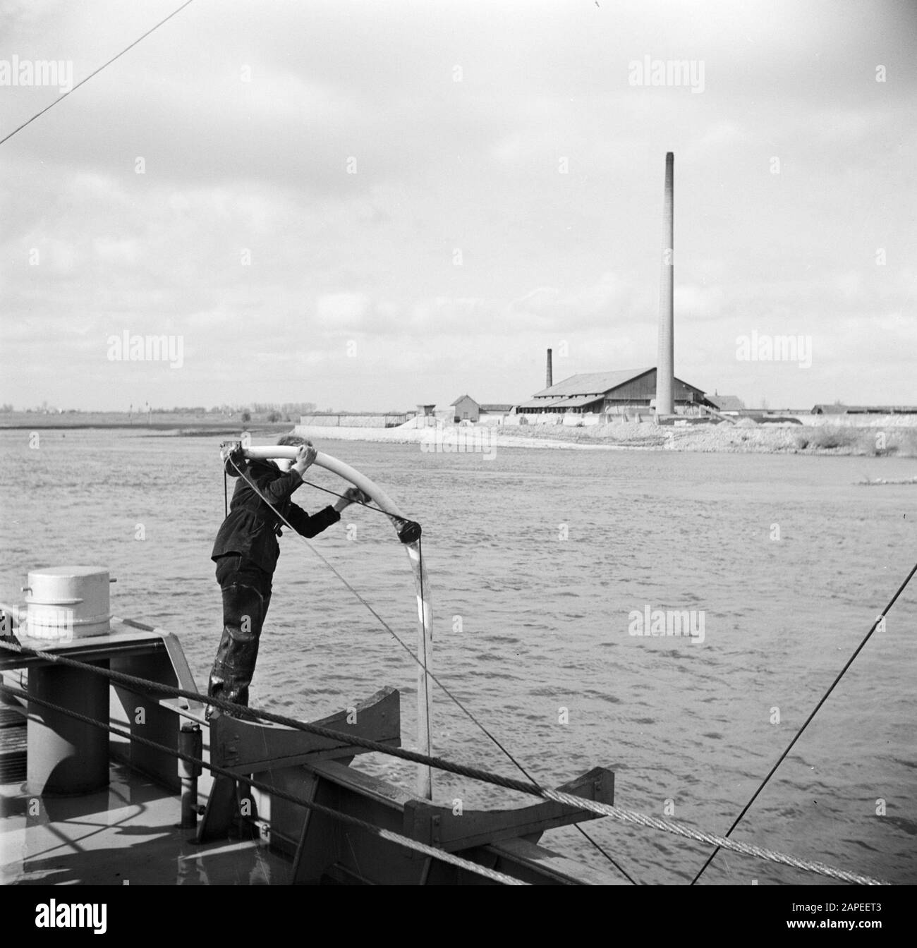 Navigation sur le Rhin, reportage sur la vie et le travail à bord d'un navire du Rhin Description: Le membre de l'équipage Otto polit le davit d'un bateau de sauvetage du damco 9, en arrière-plan une usine de briques Date: 1 avril 1955 mots clés: Industrie de la brique, rivières, skippers, nettoyage, cheminées, remorqueurs Banque D'Images