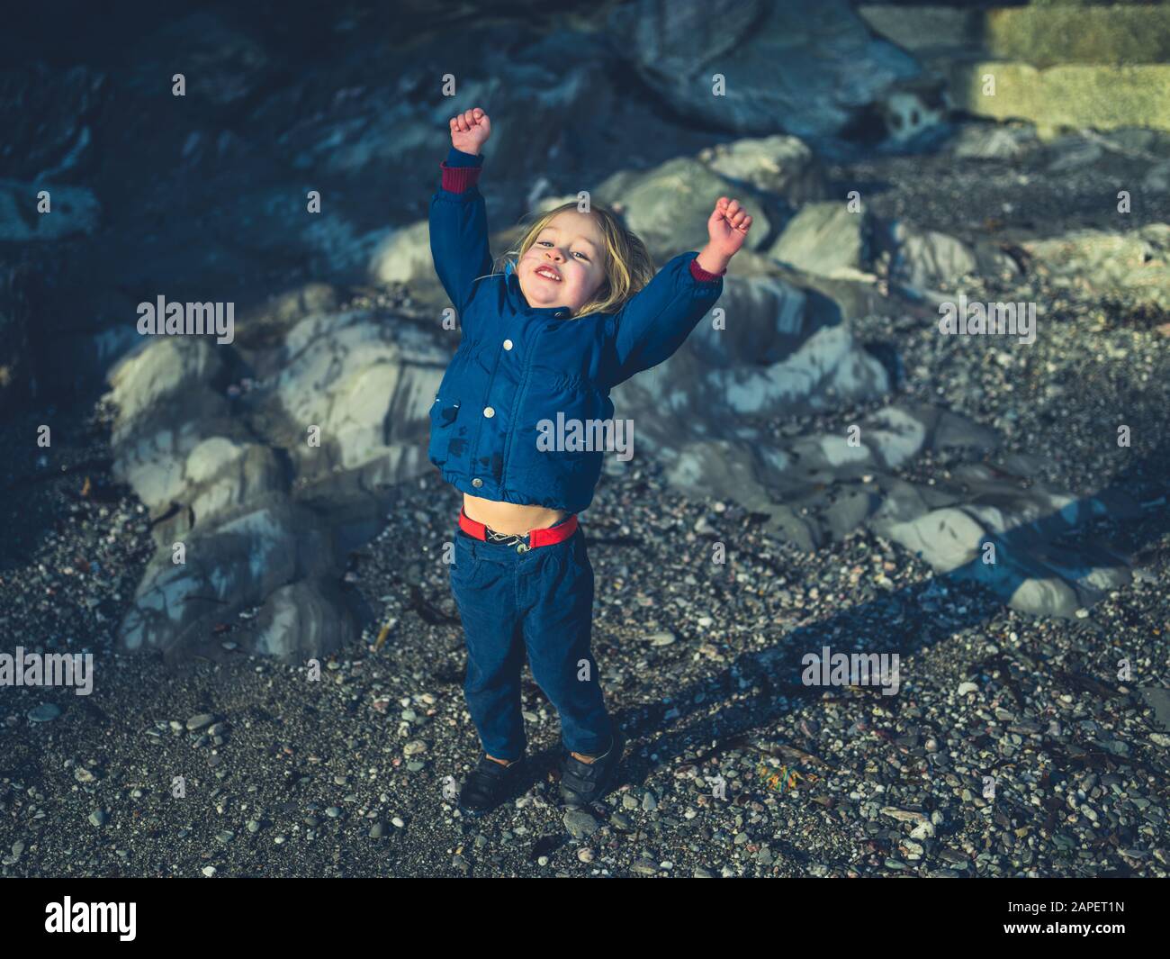 Un tout-petit excité jette ses bras sur la côte un jour d'hiver Banque D'Images