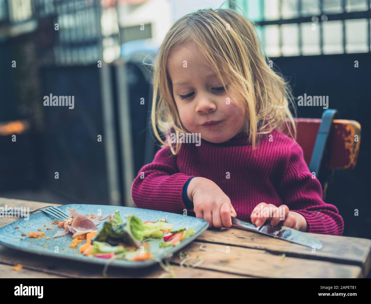 Un petit enfant prend son déjeuner dans un café Banque D'Images