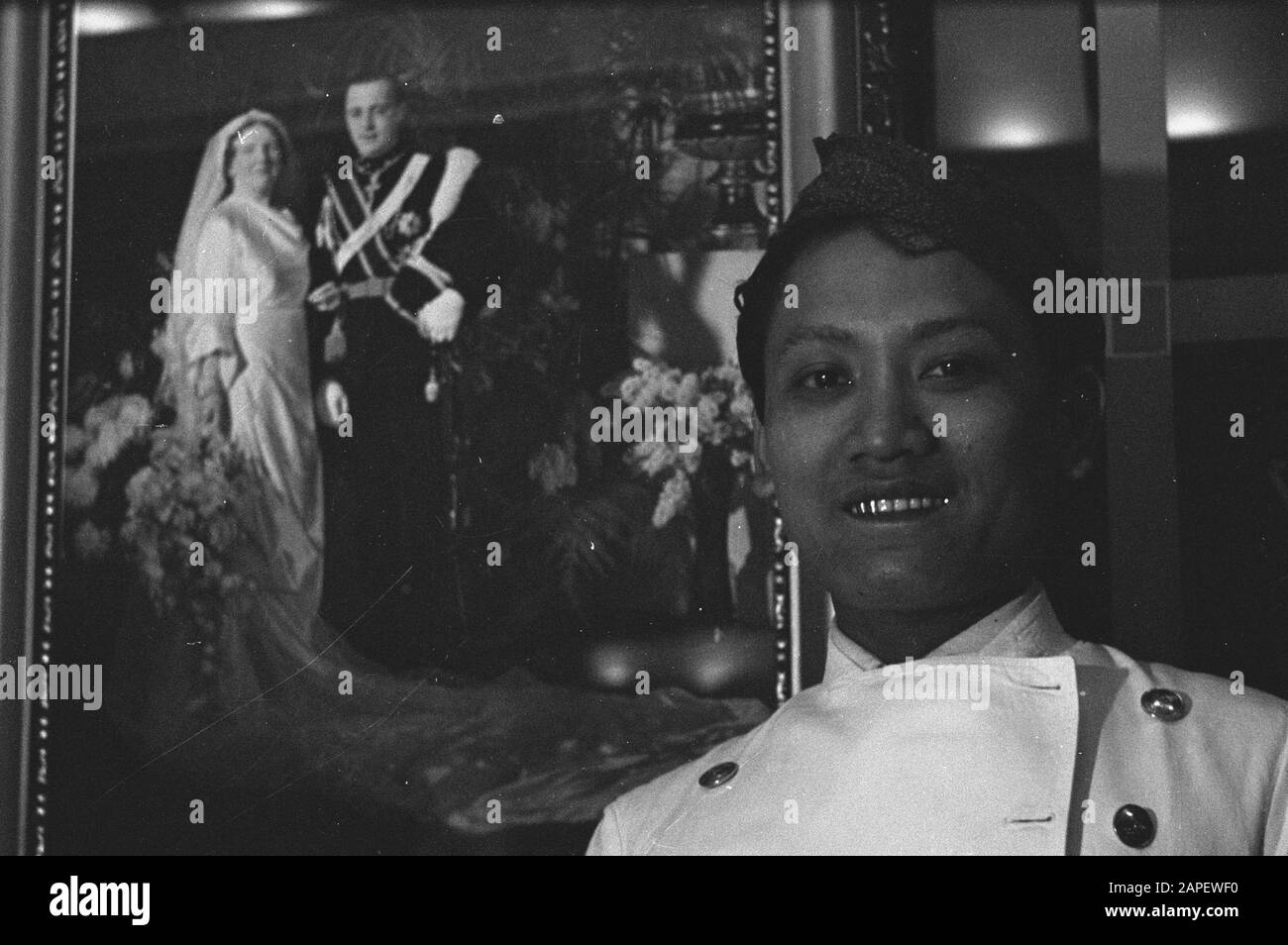 Mn [Marine marchande]/Anefo London series Description: Légende: Steward indonésien dans la salle d'état de l'ancien paquebot néerlandais de luxe [steward indonésien du navire néerlandais] Annotation: En arrière-plan le portrait de mariage de la princesse Juliana et du prince Bernhard Date: Mai 1943 lieu: Indonésie, Pays-Bas mots clés: Monarchie, navires à passagers, expédition, employés Banque D'Images