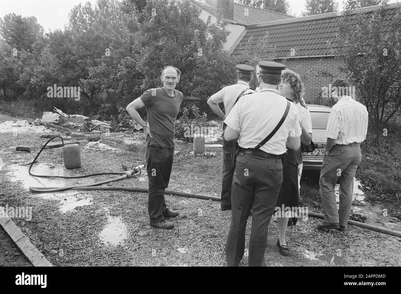 Les pompiers qui regardent le réservoir de carburant de 15 F qui s'est écrasé à Ingen; M. Walbeek (l) dans le jardin où le réservoir a atterri/Date: 18 juin 1986 mots clés: Jardin, pompiers Banque D'Images