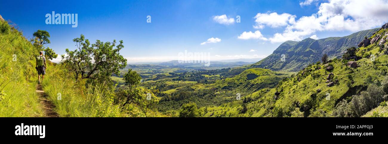 L'homme randonnée sur un petit sentier avec vue panoramique sur les montagnes escarpées et vertes une journée ensoleillée, Drakensberg, réserve de jeux du château de Giants, Afrique du Sud Banque D'Images