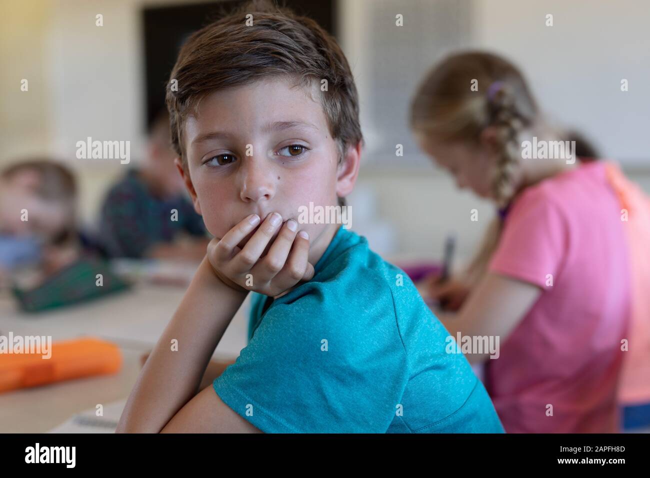 Un écolier assis à un bureau dans une salle de classe de l'école primaire Banque D'Images