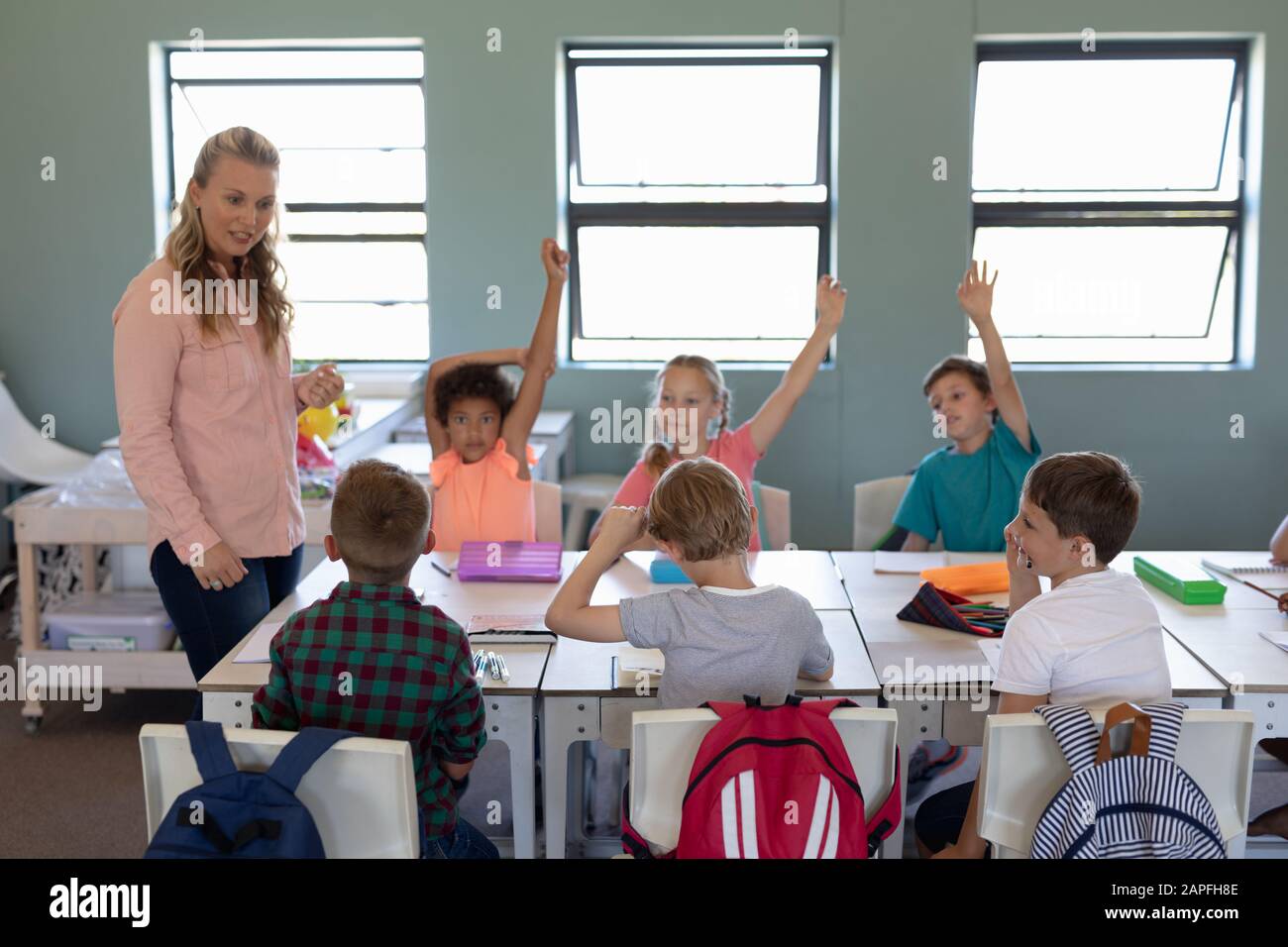 Professeur de femme avec de longs cheveux blonds debout dans une salle de classe Banque D'Images