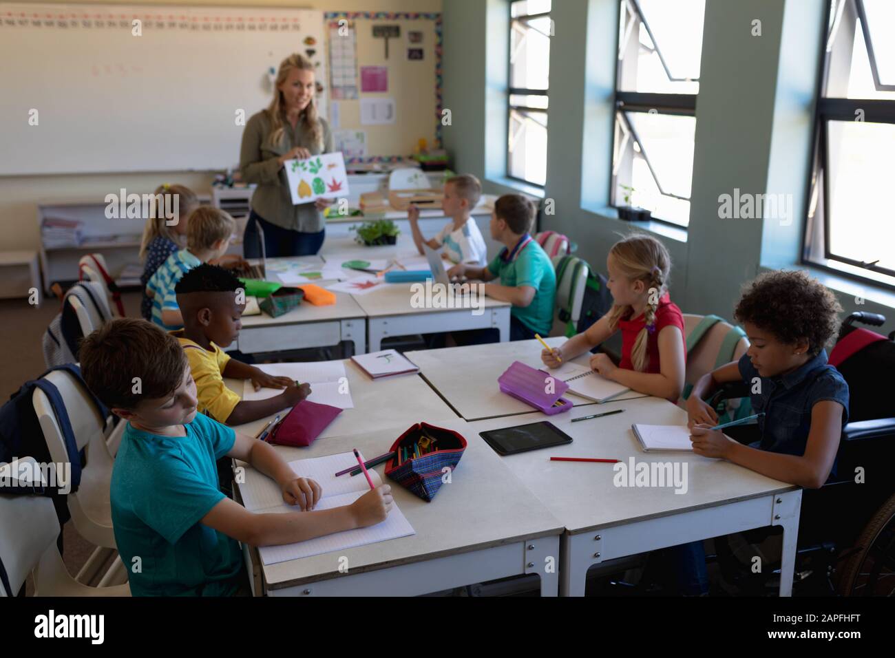 Professeur de femme avec de longs cheveux blonds debout dans une salle de classe Banque D'Images