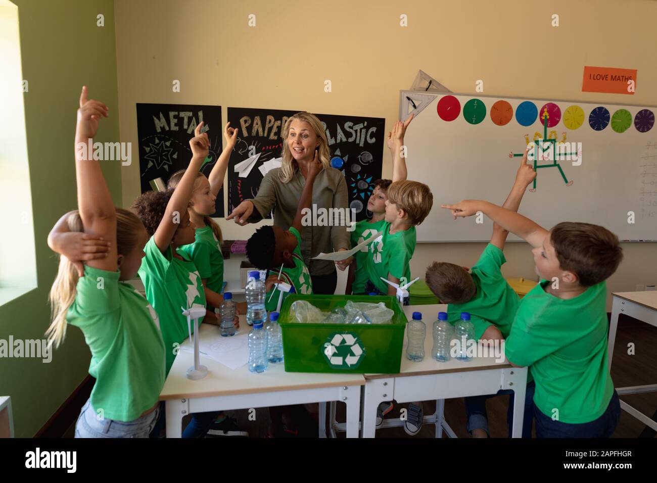 Professeur d'école féminine avec un groupe d'écoliers portant des t-shirts verts avec un recyclage blanc l Banque D'Images