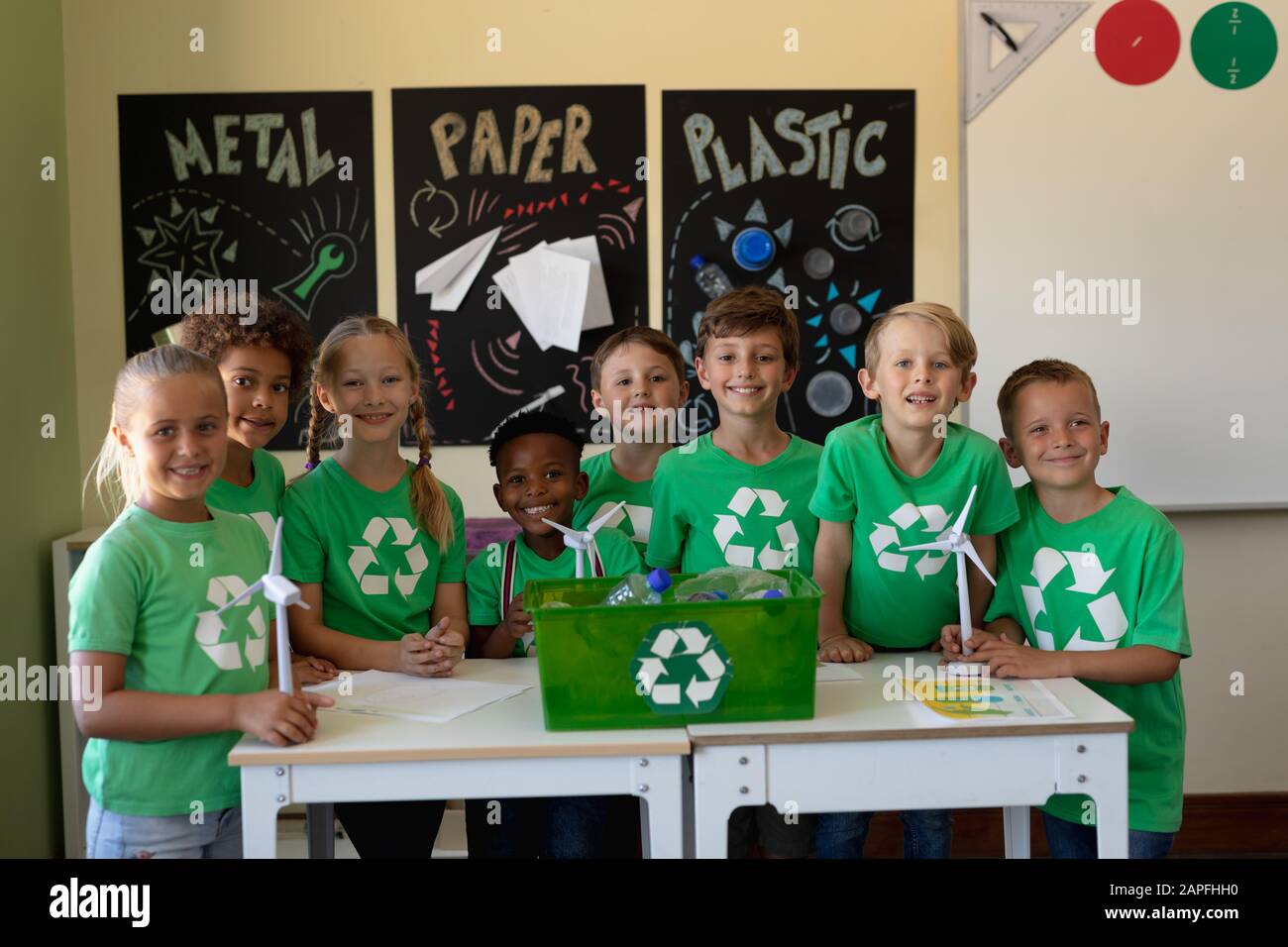 Groupe d'écoliers portant des t-shirts verts avec un logo de recyclage blanc sur eux Banque D'Images