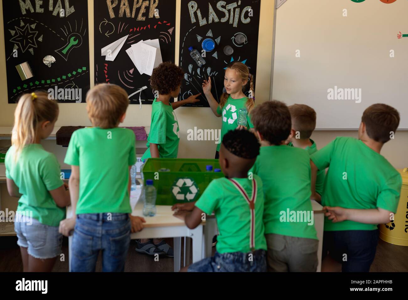 Groupe d'écoliers portant des t-shirts verts avec un logo de recyclage blanc sur eux Banque D'Images