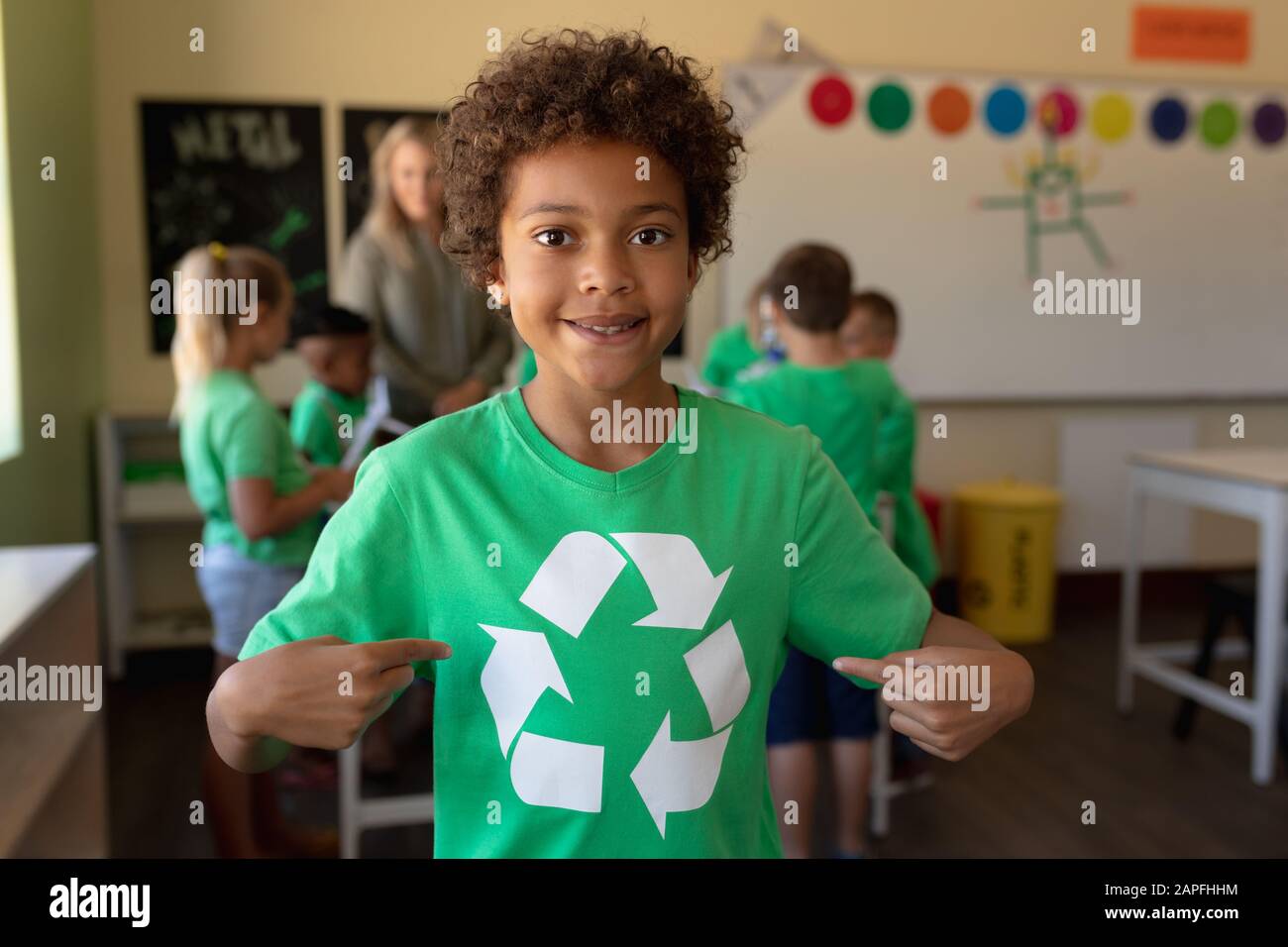 L'écolier porte un t-shirt vert avec un logo de recyclage blanc Banque D'Images