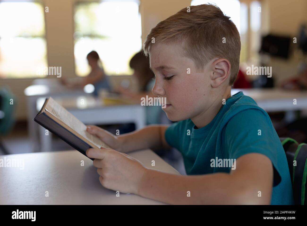 Un écolier assis à un bureau dans une salle de classe de l'école primaire Banque D'Images
