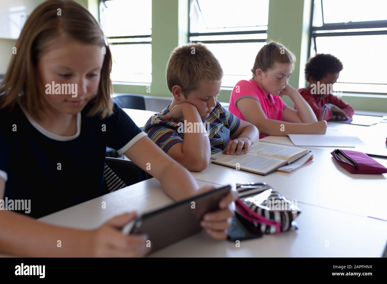 Groupe d'écoliers assis à un bureau dans une salle de classe de l'école primaire Banque D'Images