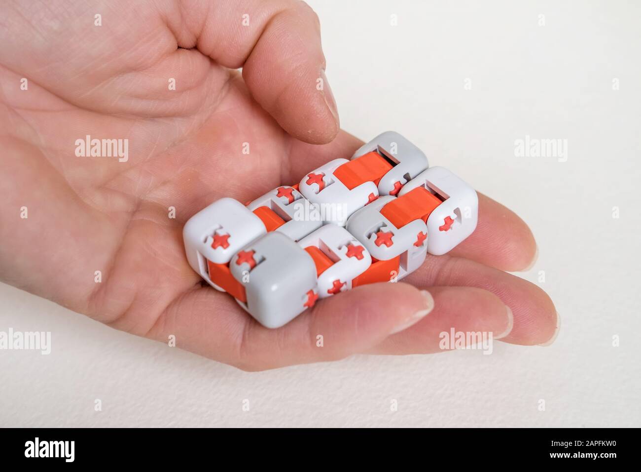 Doigts colorés antistress fidget cube jouet à la main sur fond blanc. Développement de fines compétences en moteur des doigts des enfants Banque D'Images